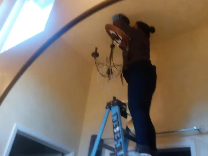 Electrician installing a chandelier in a Blaine residence
